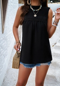 Detail of black halter top with lace trim and textured polka dot fabric on a model