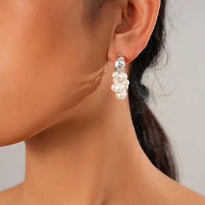 Close-up of C-shaped fringe earrings with pearls on model for vintage aesthetic