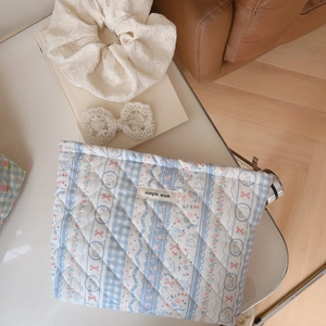 Close-up of quilted cosmetic bag with blue stripes and cute pink bow details