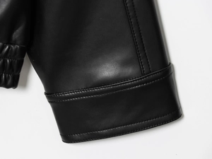 Détail du poignet d'une veste en similicuir noir montrant coutures et grain