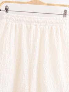 Close-up of white textured fabric showing the elastic waistband and pleated detail