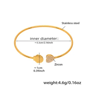 Detailed specs of gold bangle featuring zircon heart and shell inlay charms