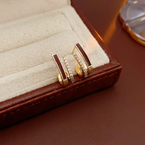 Vue macro détaillée de boucles d'oreilles en J avec émail rouge et pavé dans un écrin à bijoux