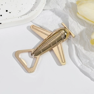 Creative gold airplane bottle opener as a metal wedding favor and gift on a white plate