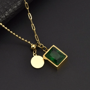 Macro shot of gold square emerald pendant necklace on black leather texture