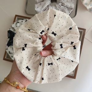Close-up of creamy white cotton scrunchie with black polka dots and mini bow print