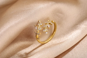 Detail of adjustable gold leaf ring with white cubic zirconia on champagne silk