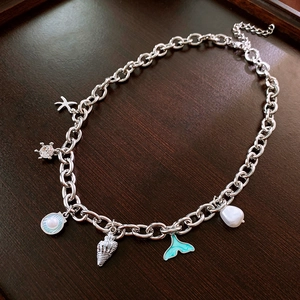 Detailed macro view of silver ocean-themed pendants with starfish, shell and pearl charms