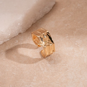 Detailed view of gold irregular textured rings on a minimalist beige background