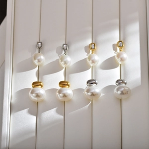 Detailed view of vintage pearl earrings with rhinestone and metal ball accents