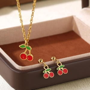 Set collana e orecchini a ciliegia dorati con frutti in smalto rosso e foglie verdi
