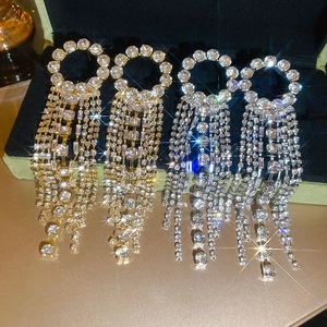 Close-up of sparkling rhinestone tassel earrings in gold and silver on black velvet
