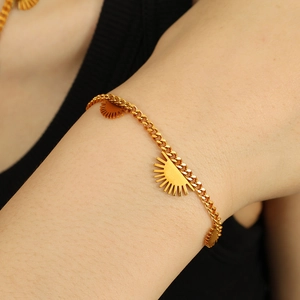Goldene Gliederkette mit Sonnenanhängern im Hip-Hop-Stil am Handgelenk eines Models