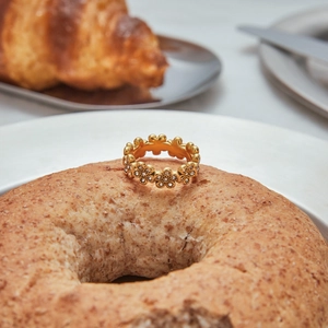 Detailed view of 18K gold flower ring with zircons placed on a bagel for lifestyle display