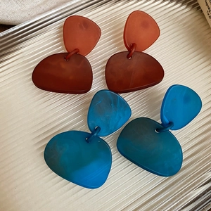 Macro detail of irregular geometric acrylic earrings in translucent red and blue marble