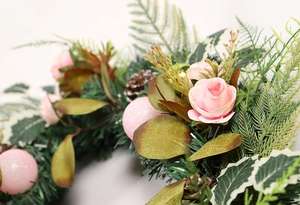 Close-up of pink roses and pine cones on a decorative Christmas wreath with glitter ornaments