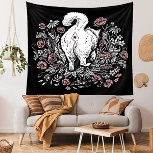 Detail of bohemian tapestry featuring a white cat and pink flowers on a minimalist living room wall