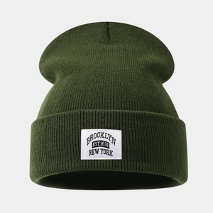 Detail of dark green ribbed knit beanie with white Brooklyn Brooklyn Est. 1631 patch