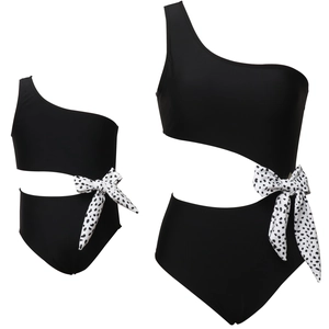 Detail of one-shoulder cutout swimsuit with polka dot bow accent in black