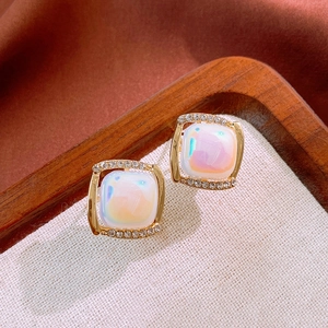 Macro shot of square gold earrings with iridescent white opal and crystal accents