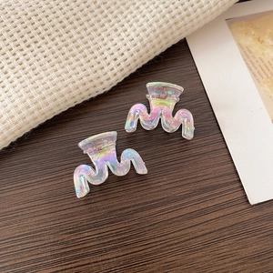 Close-up of mini iridescent butterfly hair claws with translucent wave design on wood