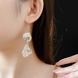 Gros plan d'un mannequin portant des boucles d'oreilles en coquillage au fini argenté