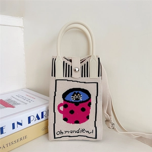 Detail of beige knitted crossbody bag featuring black cat embroidery and long shoulder strap