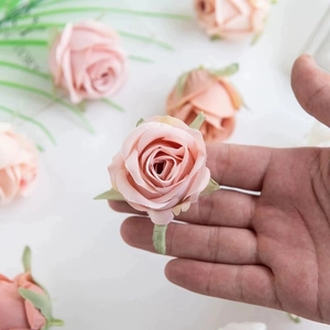 Pink silk faux rose head for DIY crafts held in hand with soft layered petals