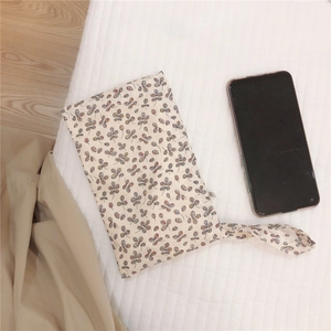 Floral cotton pouch with wristlet shown next to a smartphone for size reference