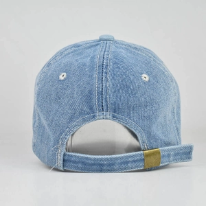 Detail view of washed denim baseball cap with adjustable antique brass metal buckle