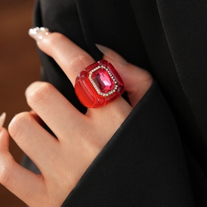 Gros plan d'une bague vintage en résine rouge avec zircons sur un costume noir