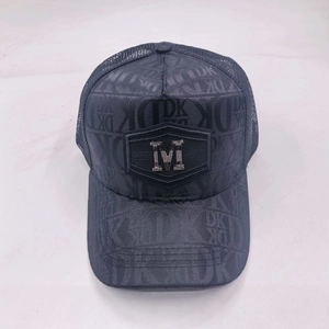 Detail of dark grey trucker hat showing metallic M logo and breathable mesh fabric