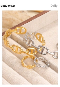 Macro view of gold and silver pig nose link bracelets and rings on a beige velvet tray
