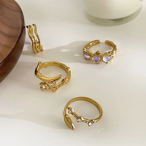 Gold moonstone ring set with wavy bands and leaf designs on a minimalist tray