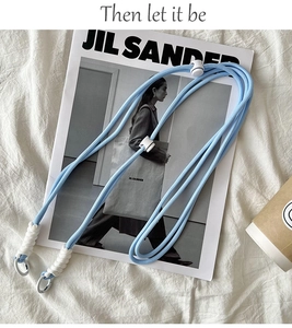 Adjustable light blue braided crossbody strap with metal clasp on aesthetic magazine background