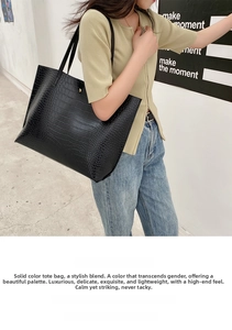Detailed view of black crocodile pattern tote bag with long shoulder strap worn by model