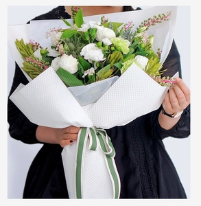 Detail of white embossed floral wrapping paper with textured grid and striped ribbon