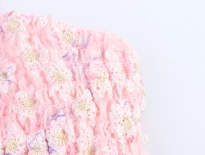 Détail du tissu smocké rose avec broderie florale blanche et dorée pour robe d'été