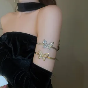 Detailed view of glittering crystal butterfly arm cuffs in gold and silver finish