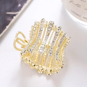 Elegant gold claw clip with sparkling rhinestones and pearls on a white surface