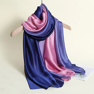 Detail eines Seidenschals mit blau-rosa Farbverlauf an einem hölzernen Kleiderbügel