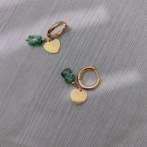 Détail de boucles d'oreilles cœur doré avec motif étoile et pierres naturelles vertes