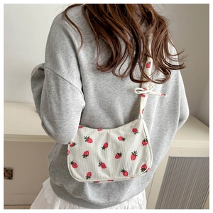 Detail of strawberry print corduroy shoulder bag featuring a decorative ribbon tie strap