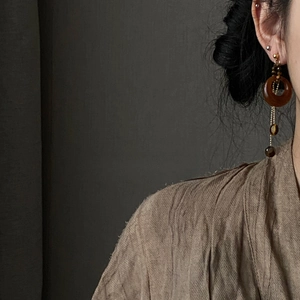 Detail view of asymmetric amber resin drop earrings with silver pins on a model