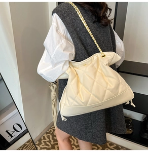 Cream quilted leather bucket bag with gold chain strap shown on model shoulder