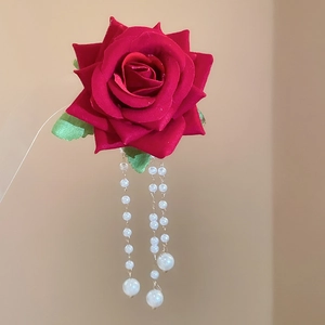 Detail of red fabric rose hair clip featuring elegant white pearl tassel drops