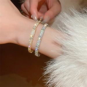Detailed view of silver and gold zircon bracelets on model with elegant winter background