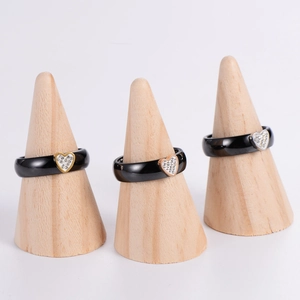 Polished black ceramic heart rings with gold and silver crystal accents on wood stands
