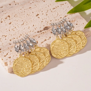 Détail de glands en pièces d'or vintage et clous en strass sur fond de pierre texturée