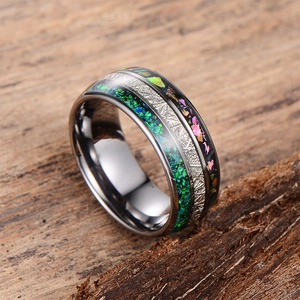 Polished black tungsten ring with emerald opal and silver meteorite inlay on wood